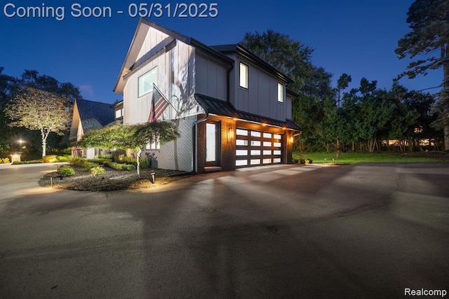 1367 W Long Lake Rd, Bloomfield Hills, MI 48302 - view of front of house featuring a standing seam roof, an attached garage, asphalt driveway, metal roof, and board and batten siding