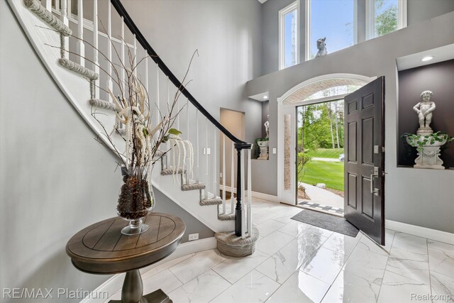 4298 Emu Dr, Pinckney, MI 48169 - entryway featuring stairs, marble finish flooring, baseboards, and a towering ceiling