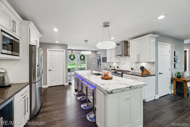 4298 Emu Dr, Pinckney, MI 48169 - kitchen featuring wall chimney exhaust hood, stainless steel appliances, a center island with sink, a sink, and recessed lighting