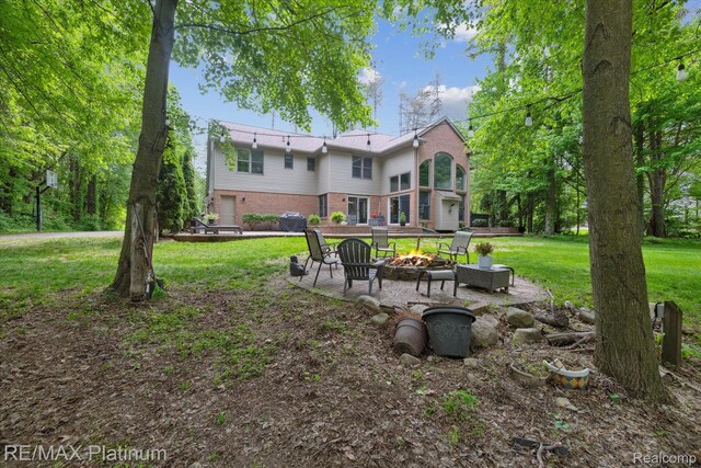 4298 Emu Dr, Pinckney, MI 48169 - rear view of house with a fire pit, brick siding, a yard, and a patio