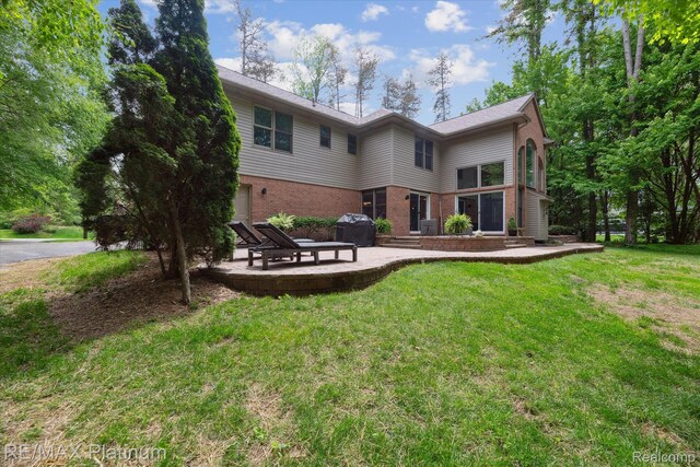4298 Emu Dr, Pinckney, MI 48169 - back of house featuring a patio, brick siding, and a yard