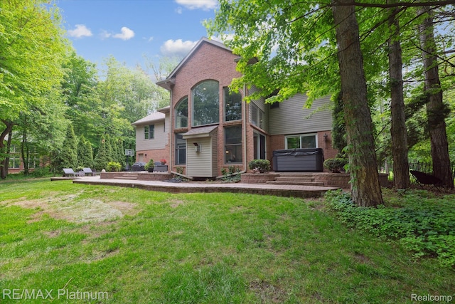 4298 Emu Dr, Pinckney, MI 48169 - rear view of house featuring brick siding, a hot tub, a yard, and a patio