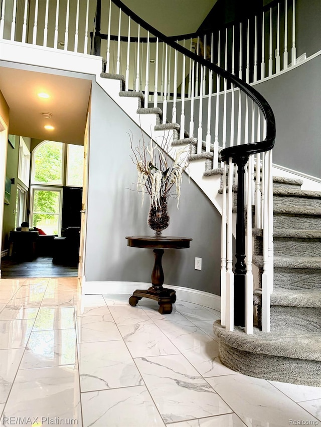 4298 Emu Dr, Pinckney, MI 48169 - stairs featuring marble finish floors, baseboards, and a high ceiling