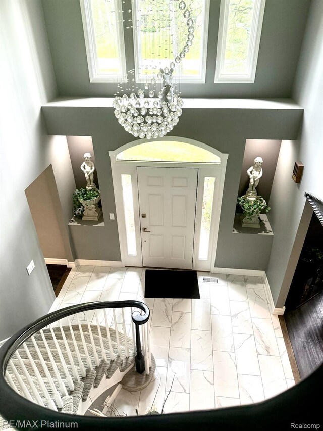 4298 Emu Dr, Pinckney, MI 48169 - entryway featuring marble finish floors, baseboards, a high ceiling, and a chandelier