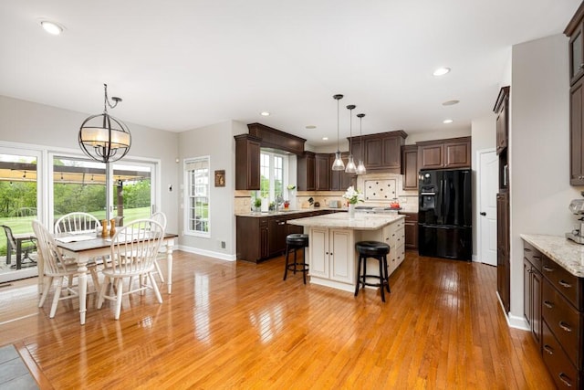 50550 W Fellows Creek Ct, Plymouth, MI 48170 - kitchen featuring black fridge with ice dispenser, a breakfast bar, dark brown cabinets, light wood-style floors, and recessed lighting
