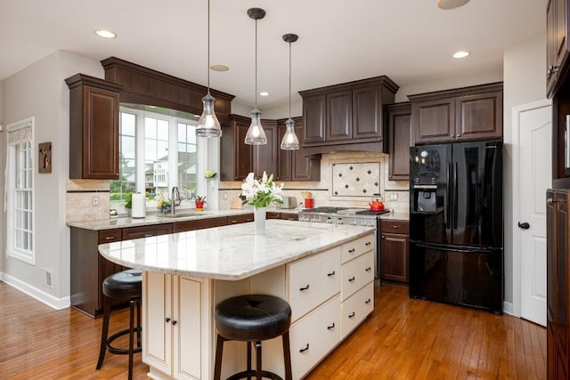 50550 W Fellows Creek Ct, Plymouth, MI 48170 - kitchen with black fridge, a sink, dark brown cabinets, a kitchen island, and a kitchen bar