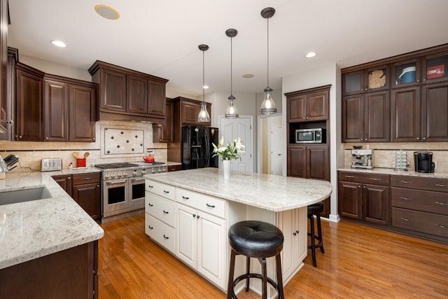 50550 W Fellows Creek Ct, Plymouth, MI 48170 - kitchen with stainless steel appliances, backsplash, white cabinetry, a breakfast bar area, and dark brown cabinetry