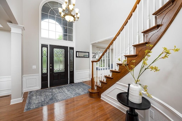 50550 W Fellows Creek Ct, Plymouth, MI 48170 - entrance foyer with wood finished floors, a chandelier, a wainscoted wall, stairs, and a towering ceiling