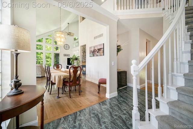 13135 Eagle Ct, South Lyon, MI 48178 - dining space with high vaulted ceiling, stairway, a chandelier, marble look tiles, and baseboards