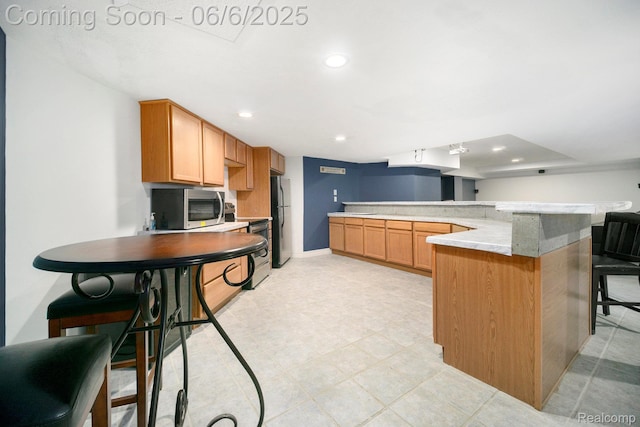 13135 Eagle Ct, South Lyon, MI 48178 - kitchen with appliances with stainless steel finishes, recessed lighting, a kitchen bar, baseboards, and a peninsula