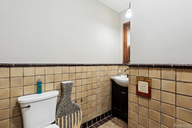 925 Avon St, Flint, MI 48503 - half bathroom featuring vanity, tile walls, toilet, tile patterned floors, and a wainscoted wall