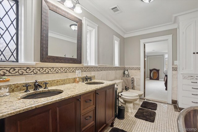925 Avon St, Flint, MI 48503 - bathroom featuring tile walls, double vanity, toilet, crown molding, and wainscoting