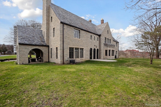 925 Avon St, Flint, MI 48503 - back of property with a chimney, a high end roof, a patio, and stone siding