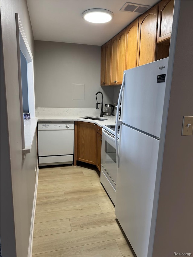 22700 Garrison St Unit 501, Dearborn, MI 48124 - kitchen featuring white appliances, a sink, light wood-style floors, light countertops, and brown cabinetry