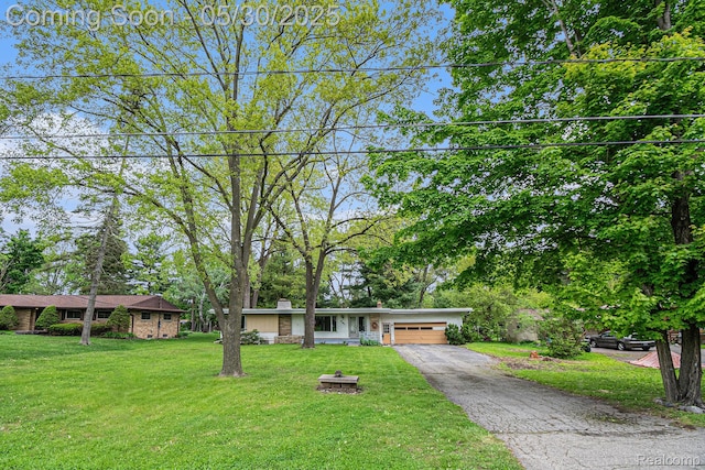 6151 Woodmoor Dr, Burton, MI 48509 - view of front facade featuring a garage, asphalt driveway, a front lawn, and a chimney