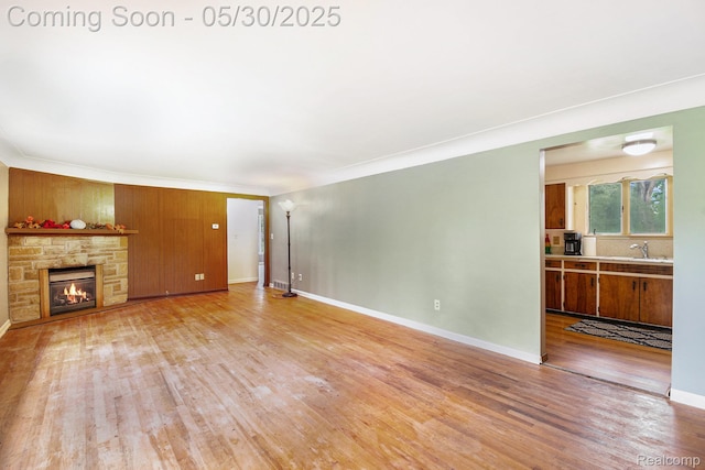 6151 Woodmoor Dr, Burton, MI 48509 - unfurnished living room featuring a sink, light wood finished floors, a fireplace, baseboards, and ornamental molding