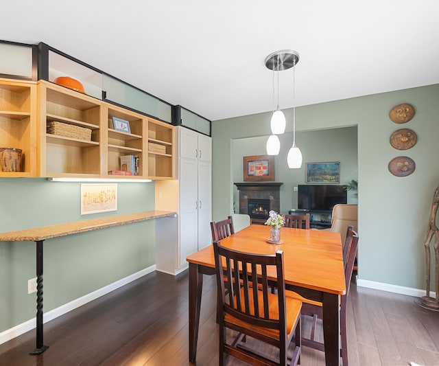 702 Starfield Dr, Pinckney, MI 48169 - dining area with a lit fireplace, dark wood-style floors, and baseboards