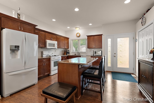 1733 Grevel Ct, Muskegon, MI 49444 - kitchen featuring white appliances, a kitchen island, decorative backsplash, recessed lighting, and a breakfast bar area