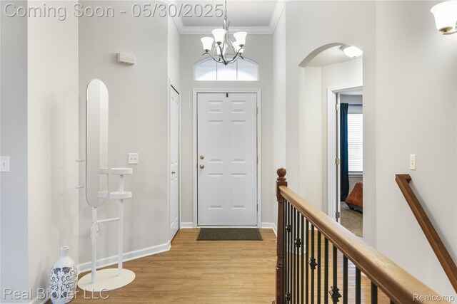 4428 Cross Creek Blvd, Burton, MI 48509 - entrance foyer with ornamental molding, arched walkways, light wood-style floors, baseboards, and a chandelier