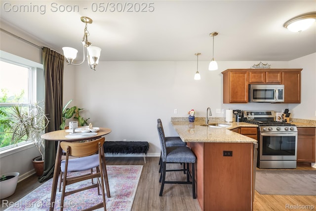 4428 Cross Creek Blvd, Burton, MI 48509 - kitchen with appliances with stainless steel finishes, a sink, a peninsula, brown cabinets, and light stone counters