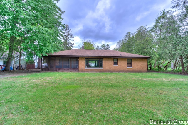 2587 Pennsylvania Ave, Muskegon, MI 49445 - view of front of house featuring a front yard, a chimney, brick siding, and a sunroom