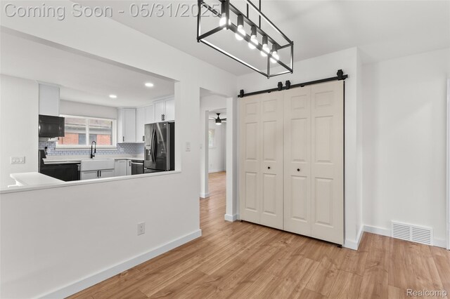 27677 Doreen St, Farmington Hills, MI 48336 - kitchen with appliances with stainless steel finishes, light wood finished floors, a barn door, tasteful backsplash, and baseboards