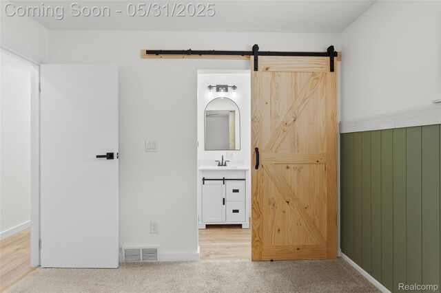 27677 Doreen St, Farmington Hills, MI 48336 - unfurnished bedroom featuring a barn door, carpet flooring, a sink, and ensuite bathroom