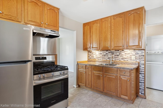 1623 Ethel Ave, Lincoln Park, MI 48146 - kitchen with stainless steel appliances, estacked washer and dryer, under cabinet range hood, tasteful backsplash, and light stone countertops