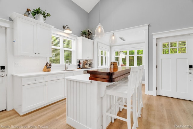 3565 Memoir Dr, Fort Gratiot, MI 48059 - kitchen with a sink, light wood-style flooring, white cabinetry, light countertops, and high vaulted ceiling