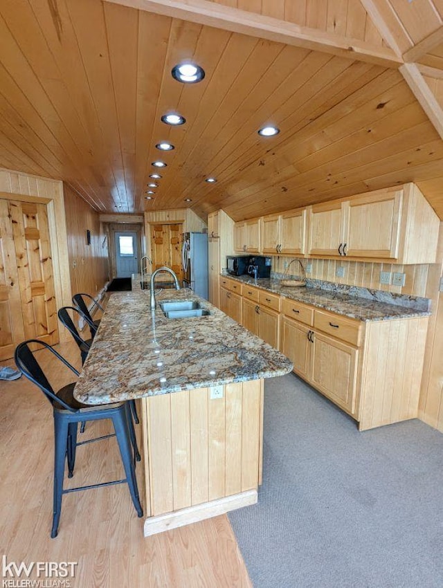 1422 Sims St, De Tour Village, MI 49725 - kitchen with a sink, light brown cabinetry, freestanding refrigerator, stone counters, and a large island with sink