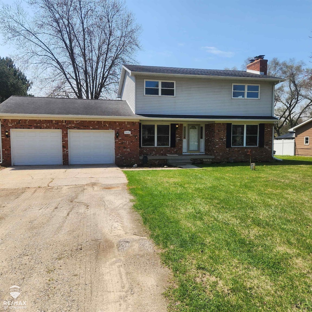 9881 W M-21 Rd, Ovid, MI 48866 - traditional home featuring a chimney, driveway, brick siding, an attached garage, and a front lawn