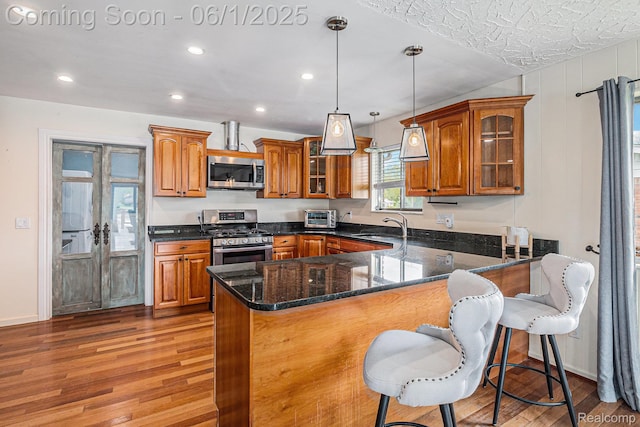 687 Sunnybeach Dr, White Lake, MI 48386 - kitchen with appliances with stainless steel finishes, brown cabinets, light wood-type flooring, a peninsula, and recessed lighting