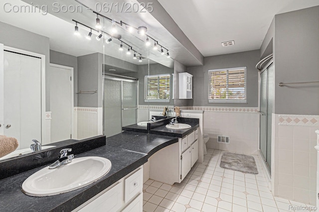 687 Sunnybeach Dr, White Lake, MI 48386 - bathroom featuring tile walls, tile patterned flooring, double vanity, a shower stall, and toilet