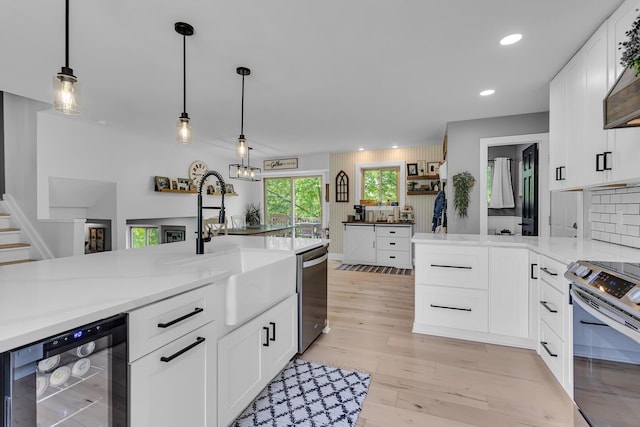 9275 M-50, Onsted, MI 49265 - kitchen with wine cooler, appliances with stainless steel finishes, a sink, white cabinets, and light countertops