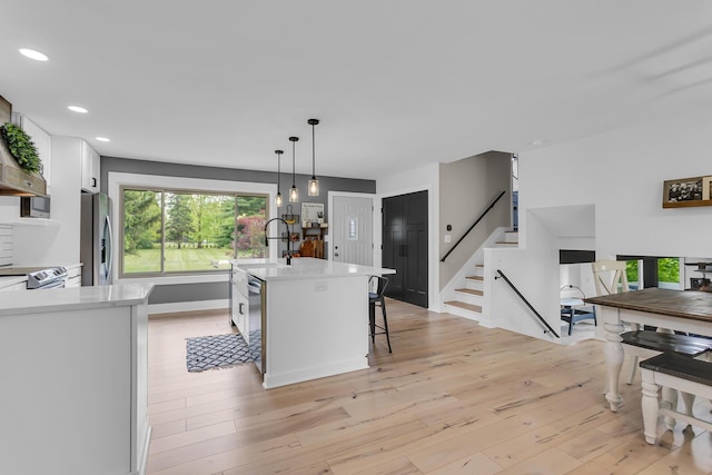 9275 M-50, Onsted, MI 49265 - kitchen with stainless steel fridge with ice dispenser, light countertops, white cabinetry, light wood-type flooring, and recessed lighting