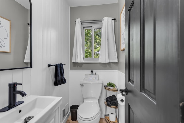 9275 M-50, Onsted, MI 49265 - half bath featuring a sink, toilet, a decorative wall, and a wainscoted wall