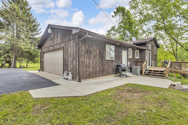 9275 M-50, Onsted, MI 49265 - view of property exterior featuring central AC unit, a deck, a garage, and a lawn