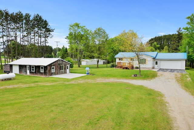1972 W Cedar Dr, Mcbain, MI 49657 - view of green lawn with dirt driveway, an attached garage, and a deck