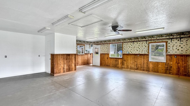 1972 W Cedar Dr, Mcbain, MI 49657 - unfurnished living room with finished concrete flooring, wood walls, wainscoting, baseboards, and a textured ceiling