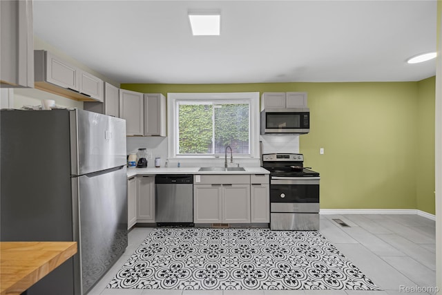 4627 Berkshire St, Detroit, MI 48224 - kitchen featuring appliances with stainless steel finishes, a sink, baseboards, light tile patterned flooring, and gray cabinets
