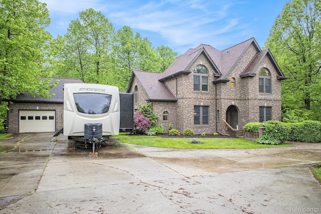 6140 Seymour Rd, Swartz Creek, MI 48473 - french country inspired facade featuring concrete driveway, brick siding, a front lawn, and an attached garage
