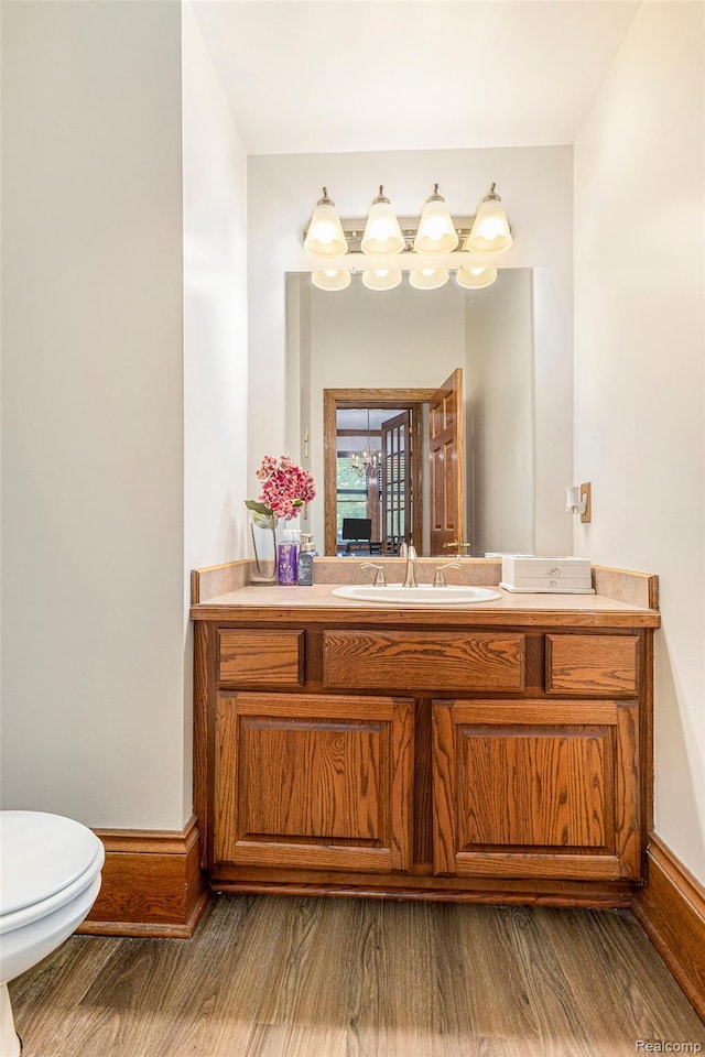 6140 Seymour Rd, Swartz Creek, MI 48473 - half bathroom with toilet, vanity, wood finished floors, and baseboards
