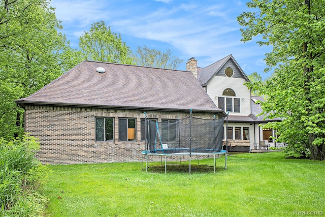 6140 Seymour Rd, Swartz Creek, MI 48473 - rear view of property featuring a trampoline, a yard, a chimney, and brick siding