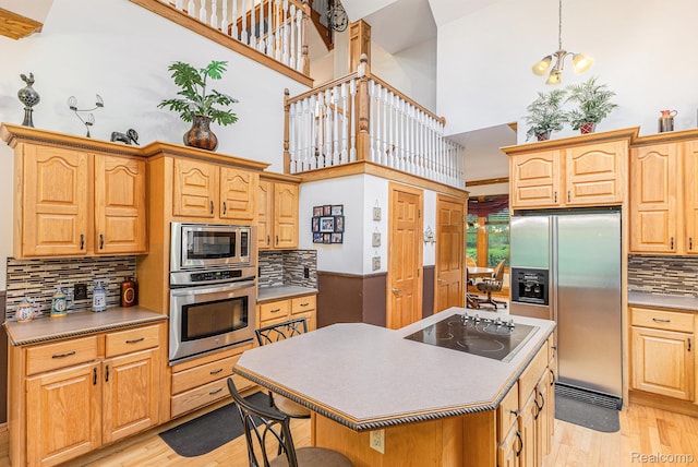 6140 Seymour Rd, Swartz Creek, MI 48473 - kitchen with appliances with stainless steel finishes, a high ceiling, light wood finished floors, backsplash, and a kitchen island