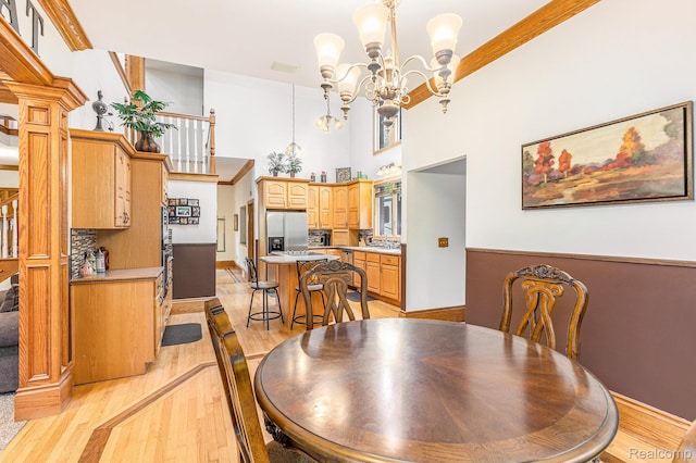 6140 Seymour Rd, Swartz Creek, MI 48473 - dining space with light wood-style floors, a high ceiling, a chandelier, and baseboards