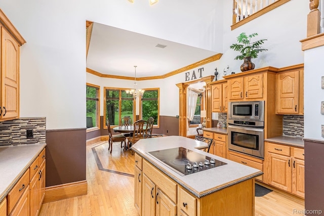 6140 Seymour Rd, Swartz Creek, MI 48473 - kitchen with stainless steel appliances, a chandelier, light wood-type flooring, a center island, and decorative backsplash