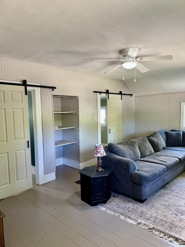 12227 Wise St, Bear Lake, MI 49614 - living room with a barn door, wood-type flooring, ceiling fan, a textured ceiling, and vaulted ceiling