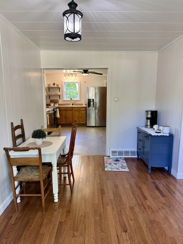 12227 Wise St, Bear Lake, MI 49614 - dining area featuring wood finished floors, ornamental molding, ceiling fan, baseboards, and wood walls