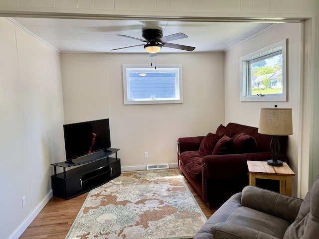 12227 Wise St, Bear Lake, MI 49614 - living area with ornamental molding, healthy amount of natural light, wood finished floors, baseboards, and a ceiling fan