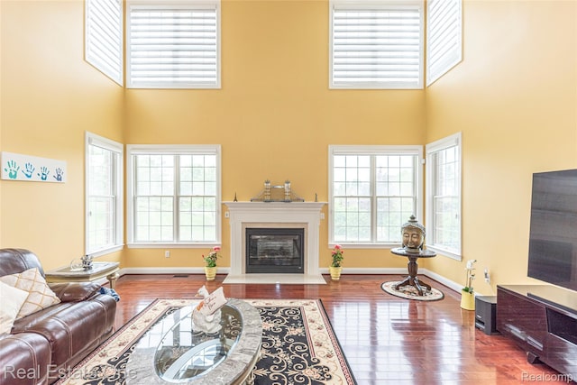 15390 Prestwick Cir, Northville, MI 48168 - living area with healthy amount of natural light, wood finished floors, a high ceiling, and a fireplace with flush hearth